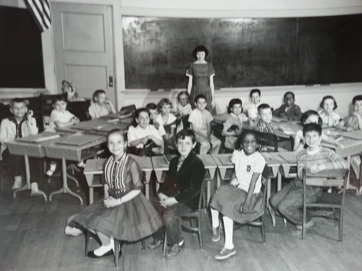 Mid-century classroom of students seated at desks with their teacher, New Britain